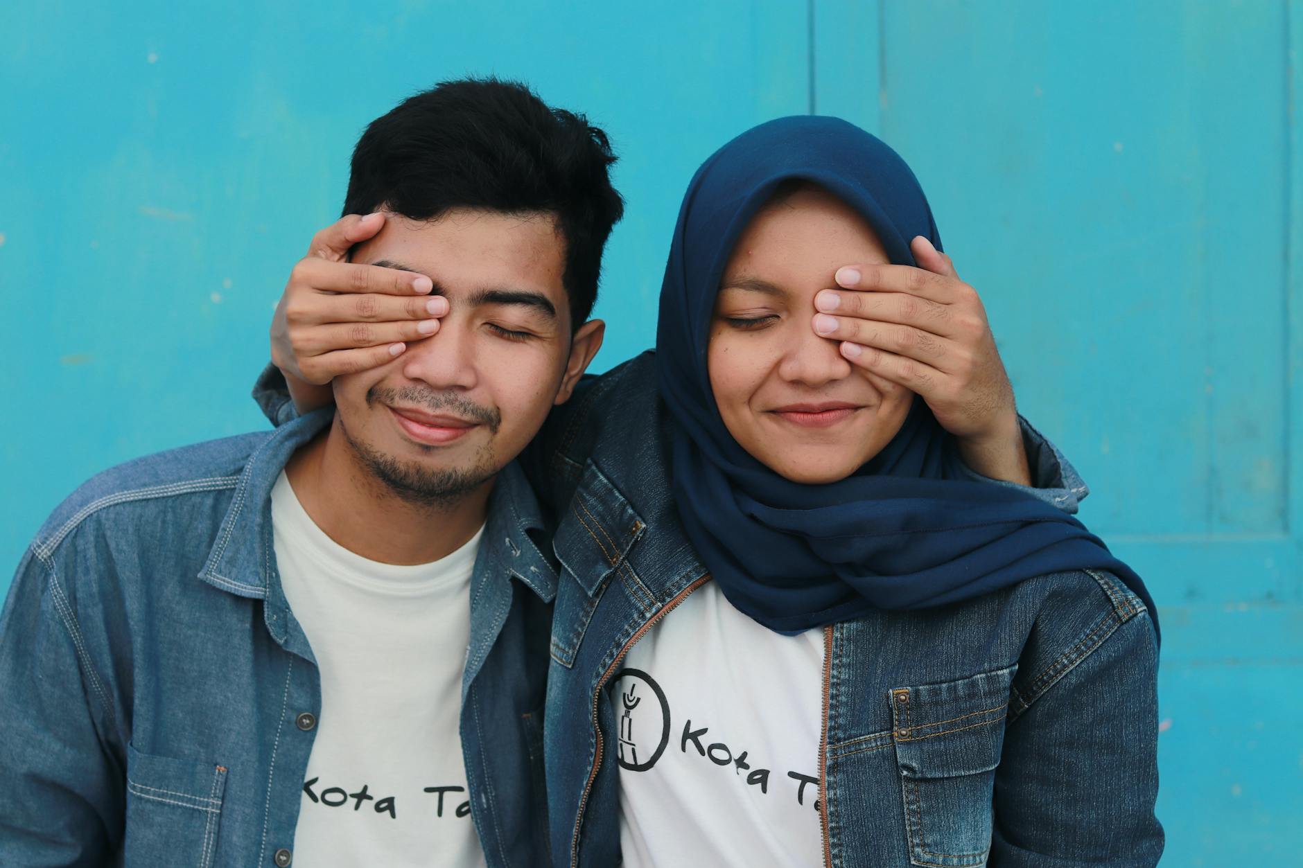 man in blue denim jacket beside woman in blue hijab