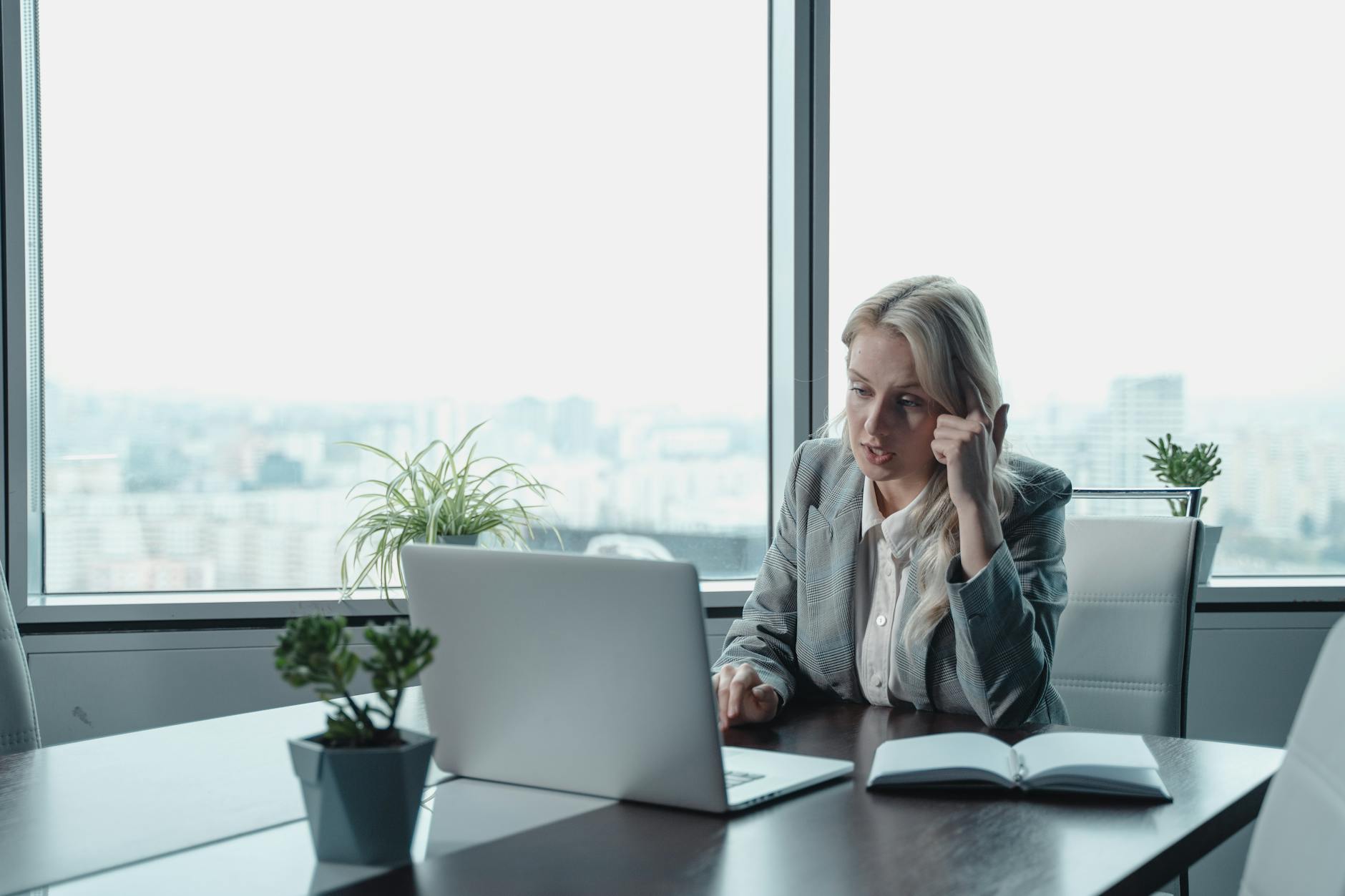 woman in gray blazer sitting in front of gray laptop computer
